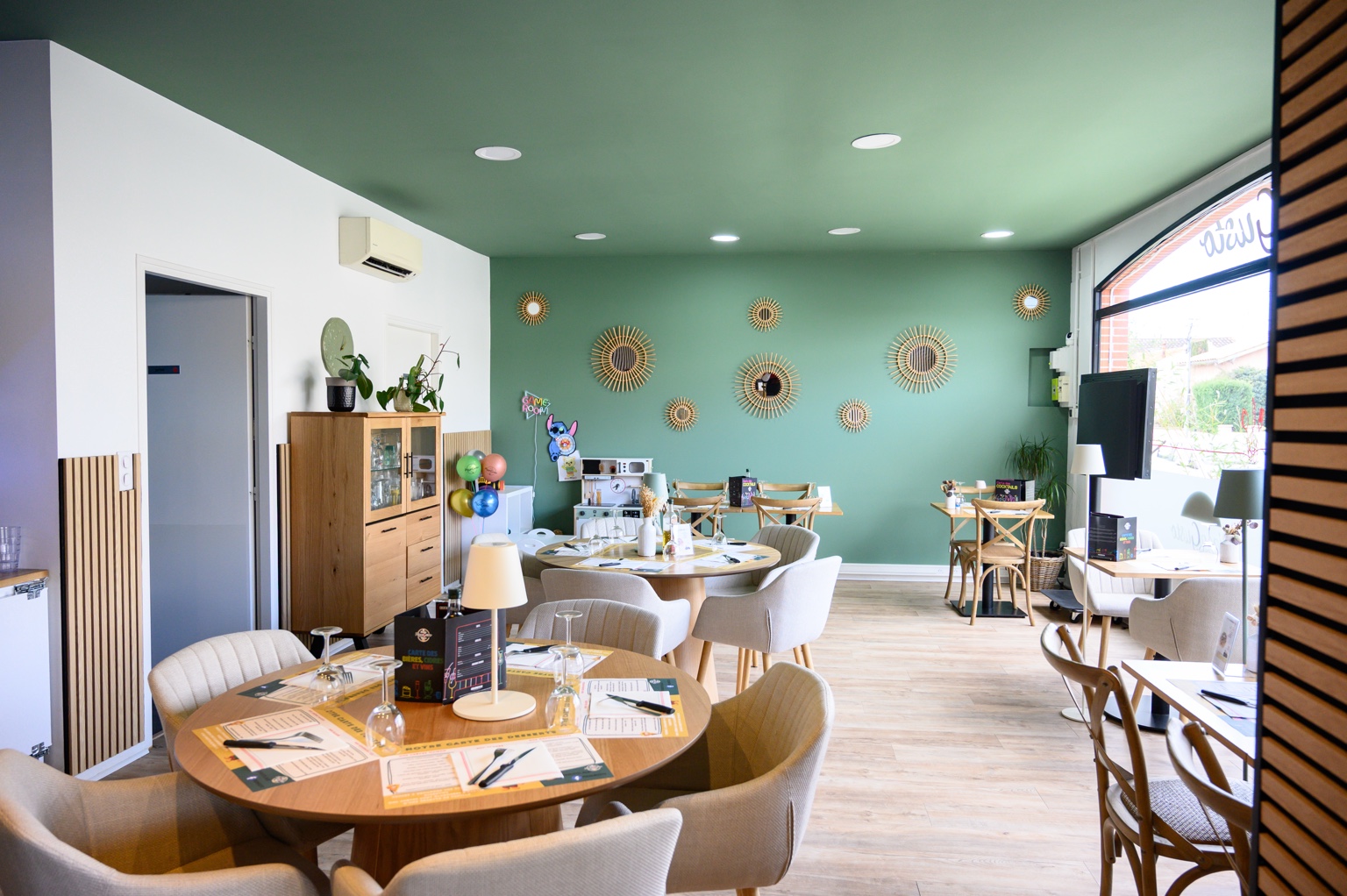La salle de Pizza Gusto à Albi, avec ses murs vert sauge, ses tables en bois dressées et le coin enfants au fond